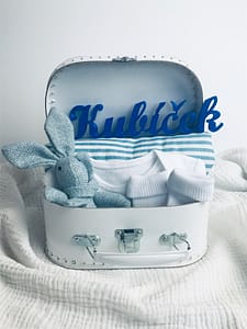 Bílý kufřík pro miminko s modrými doplňky. Obsahuje hračku zajíce, klip na dudlík, plenku a ponožky.