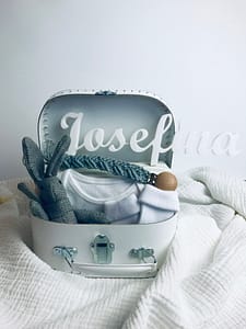 Bílý kufřík pro miminko s šedými doplňky. Neutrální barva pro obě pohlaví. Obsahuje hračku zajíce, klip na dudlík, plenku a ponožky.